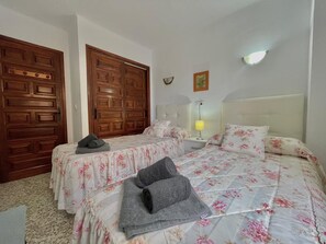 A bedroom with two beds, wooden wardrobes, a nightstand, a lamp, and a wall-mounted light fixture. - Terrasol SAN Gerardo 2-2-2 Frontal AL MAR (Velez-Malaga)