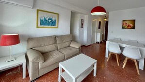 En moderne stue med sofa, sofabord og spiseplads.