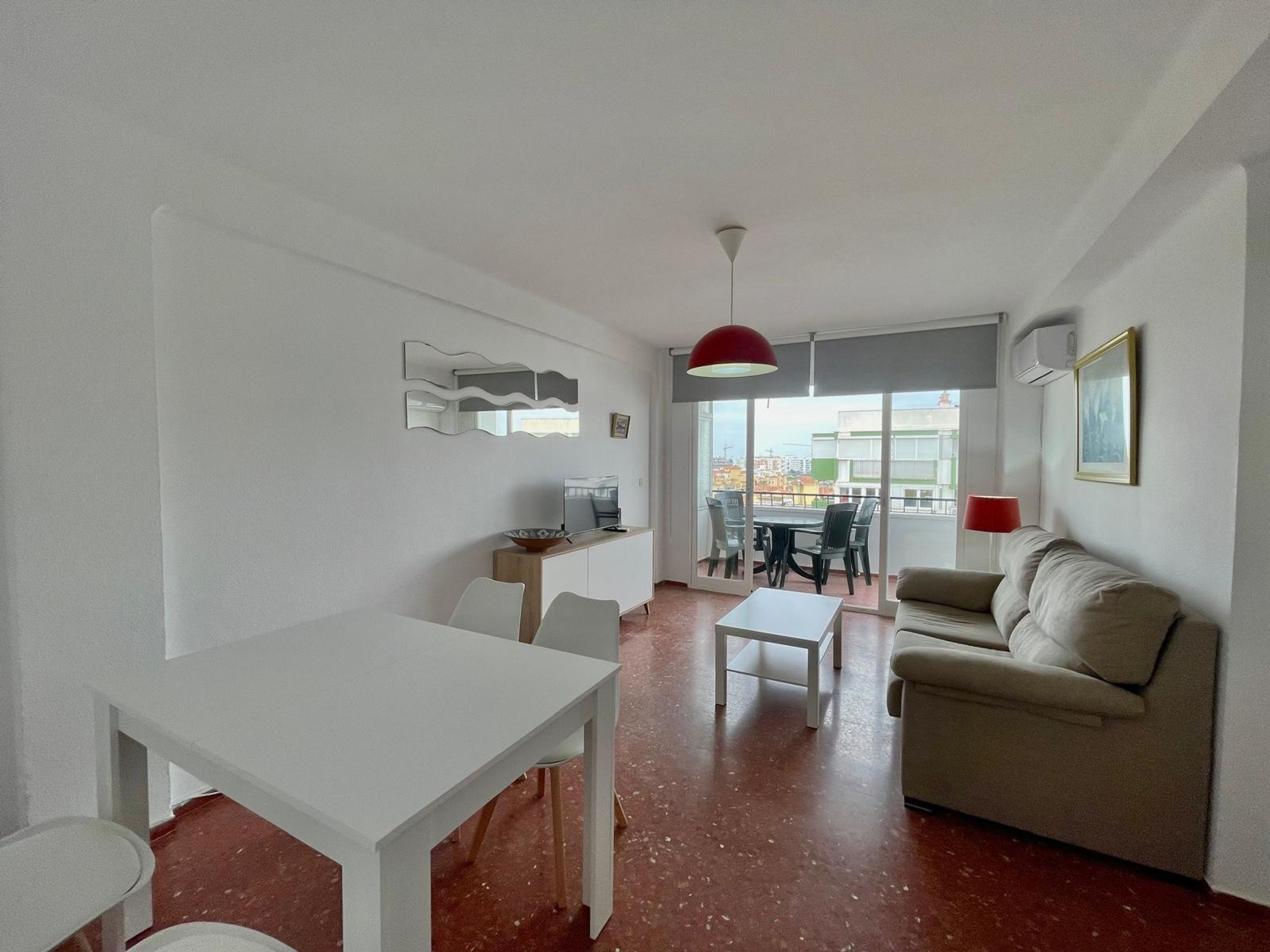 A modern living room with a dining area, a sofa, a TV, and a large window with a view.