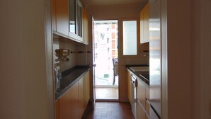 A narrow kitchen with a tiled floor, a window, and a door leading outside. - Terrasol Caracola 6-b3 (Velez-Malaga)