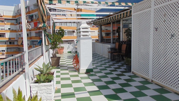 A balcony with a checkered floor, potted plants, and outdoor furniture. - Terrasol Caracola 6-b3 (Velez-Malaga)