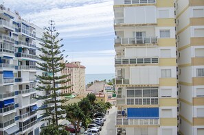 Un immeuble résidentiel à plusieurs étages, doté de balcons, d’un espace de stationnement et offrant une vue dégagée sur la mer.