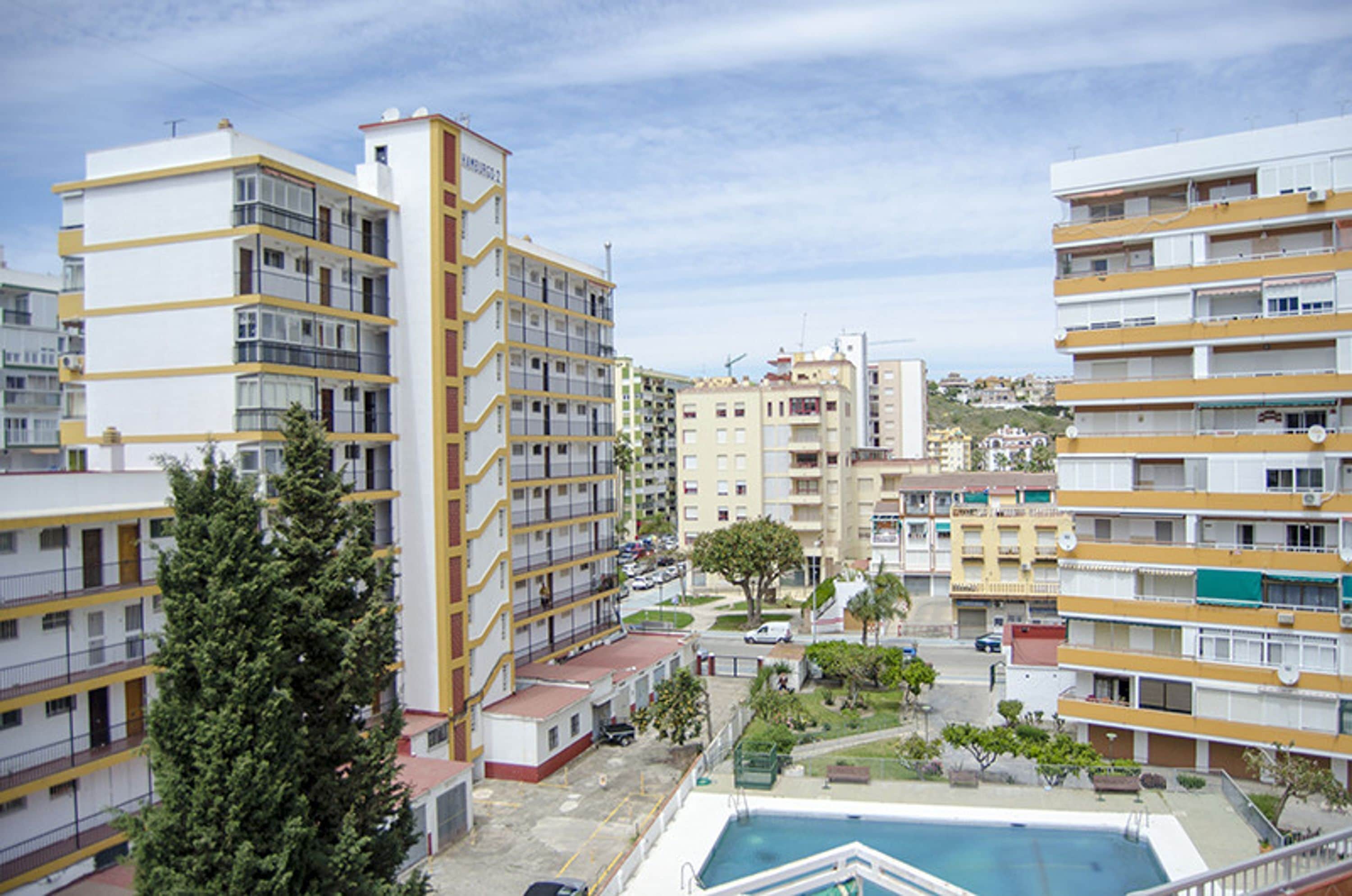 A multi-story residential building with balconies, a swimming pool, and a small park area.