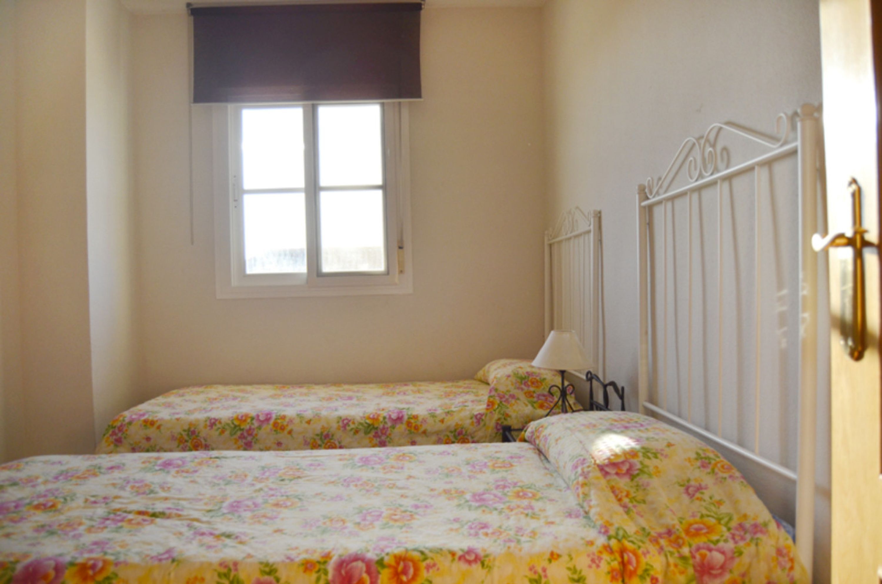 A bedroom with two beds, a window, a radiator, and a door.