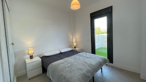 A bedroom with a bed, bedside tables, a hanging light fixture, and a sliding glass door to a balcony. - Terrasol Almunia in Algarrobo (Algarrobo)
