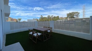 An outdoor patio with a table and chairs, surrounded by white fences and a view of buildings and trees. - Terrasol Almunia in Algarrobo (Algarrobo)