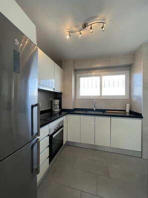 A modern kitchen with stainless steel appliances, a window, and a built-in oven. - Terrasol Arenas 4 in Torre del Mar (Velez-Malaga)