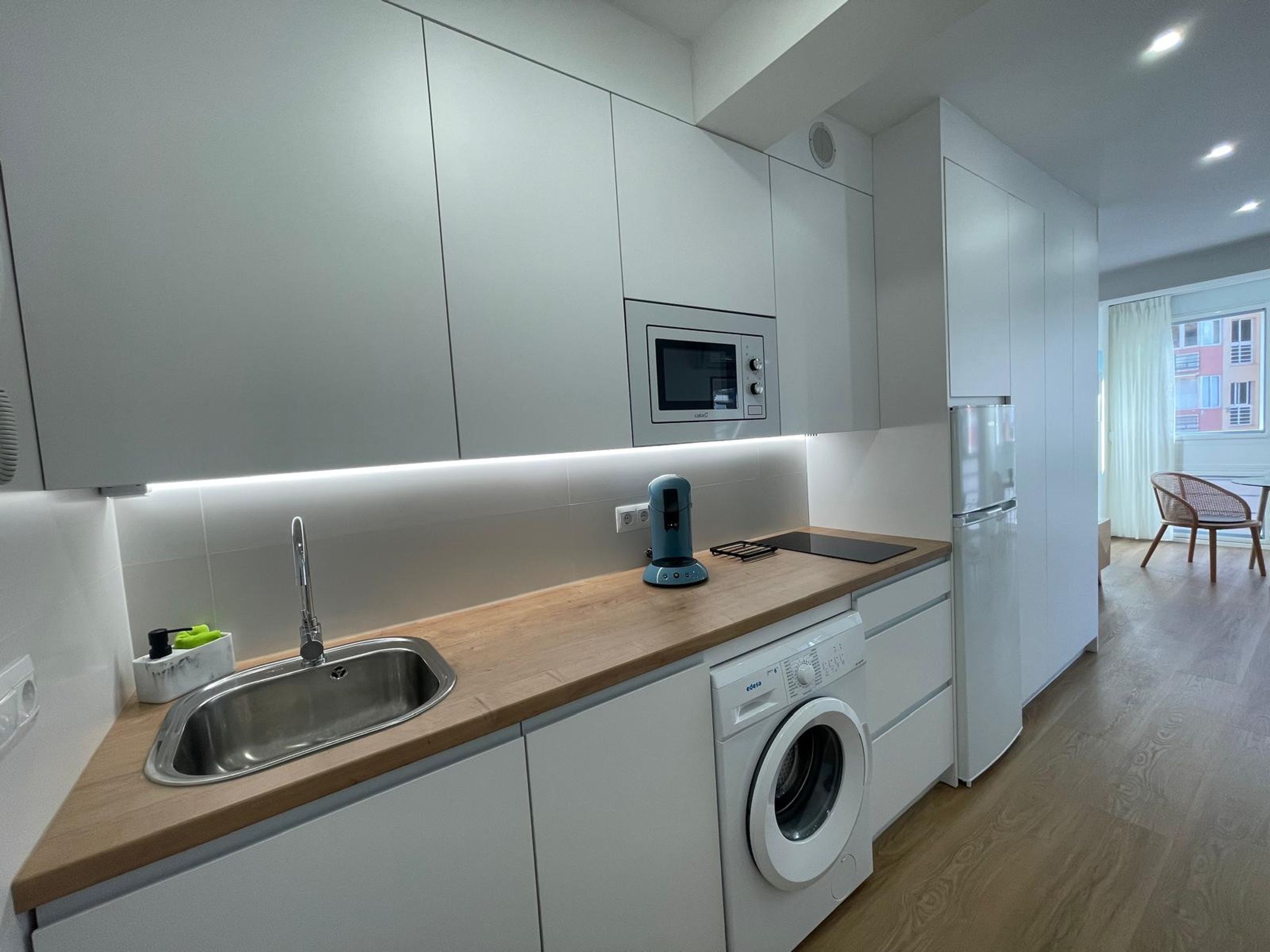 A modern kitchen with a built-in washing machine, a microwave, and a sink.