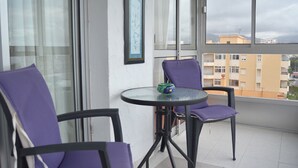 A balcony with two purple chairs, a small round table, and a framed picture on the wall. - Terrasol SAN Gerardo 2-8-2 Frontal AL MAR (Velez-Malaga)