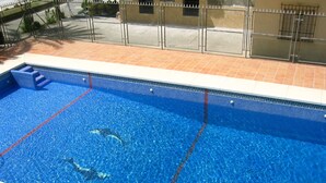 A swimming pool with clear blue water, a tiled deck, and a metal fence. - Terrasol SAN Gerardo 2-8-2 Frontal AL MAR (Velez-Malaga)