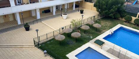 Un immeuble résidentiel doté de balcons, d’une piscine et d’un espace extérieur aménagé pour s’asseoir.