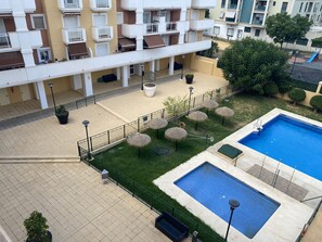 Ein Wohngebäude mit Balkonen, einem Pool und Sitzgelegenheiten im Freien.