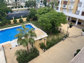 Ett bostadsområde med en swimmingpool, palmer och en basketplan.