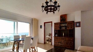 Una sala de estar con candelabro, una estantería, un comedor con sillas y un sofá.