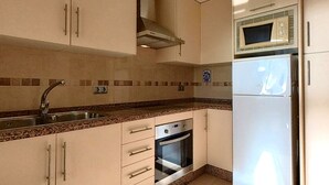 Una cocina con armarios color beige, un lavamanos de acero inoxidable, un microondas y un horno.