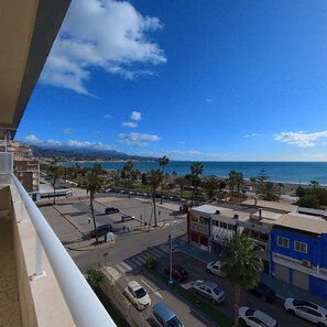 A coastal cityscape with a clear sky, buildings, and a road with parked cars. - Terrasol Frontal AL MAR Ipanema 2-5 (Velez-Malaga)