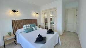 A bedroom with a bed, bedside tables, a mirror, and a wardrobe. - Terrasol Estrella DE MAR (Velez-Malaga)