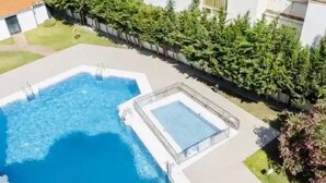 A rectangular pool with a diving board and a smaller adjacent pool, surrounded by a hedge and a building. - Terrasol Estrella DE MAR (Velez-Malaga)