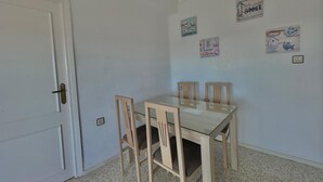A room with a white door, a glass-top table, and four wooden chairs. - Terrasol Antillas 13 (Velez-Malaga)