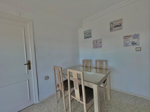A room with a white door, a glass-top table, and four wooden chairs. - Terrasol Antillas 13 (Velez-Malaga)