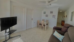 A living room with a TV, a ceiling fan, a dining table with chairs, and a sofa. - Terrasol Antillas 13 (Velez-Malaga)