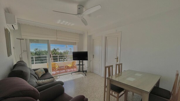 A living room with a sofa, a TV, a dining table, and chairs. - Terrasol Antillas 13 (Velez-Malaga)