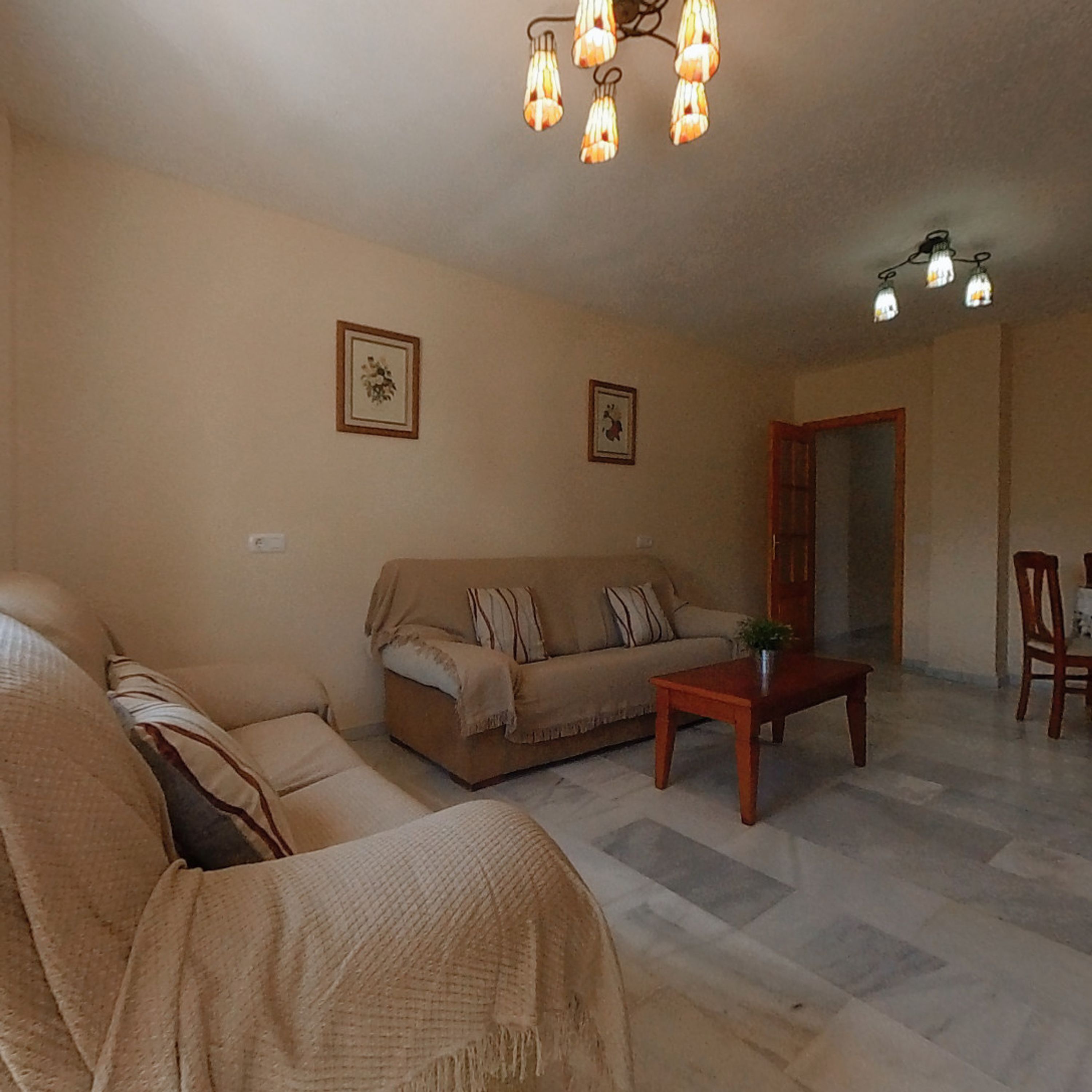 A living room with a sofa, a coffee table, and a dining area with chairs.
