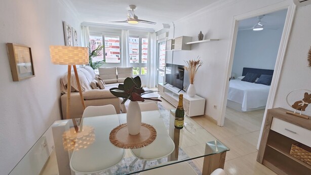 A modern living room with a glass coffee table, a sofa, a TV, and a dining area. - Terrasol Franlou Vistas AL MAR (Velez-Malaga)