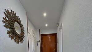 Un corridoio con pavimento decorato, una porta in legno e uno specchio fissato al muro.