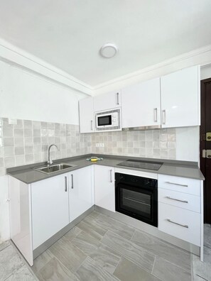 A modern kitchen with white cabinets, a microwave, a sink, and a dishwasher. - Terrasol Ahumada 1 in Torre del Mar (Velez-Malaga)