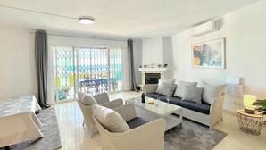 A modern living room with a sofa, two armchairs, a coffee table, and a fireplace. - Terrasol Villa Independiente Y Apartamento (Velez-Malaga)