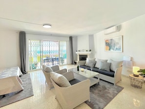 A modern living room with a sofa, two armchairs, a coffee table, and a fireplace. - Terrasol Villa Independiente Y Apartamento (Velez-Malaga)