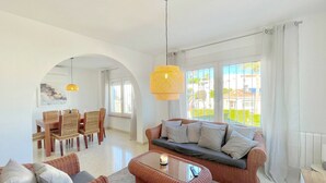 A living room with wicker furniture, a glass coffee table, and a dining area with a table and chairs. - Terrasol Villa Independiente Y Apartamento (Velez-Malaga)