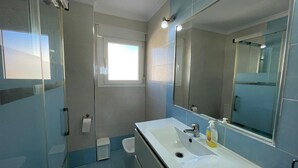 A bathroom with a large mirror, a sink, a toilet, and a glass shower enclosure. - Terrasol Rismar 4 in Torre del Mar (Velez-Malaga)