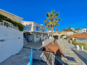 A coastal street with white buildings, a palm tree, and a clear blue sky. - Terrasol Villa Independiente Caleta DE SOL (Velez-Malaga)