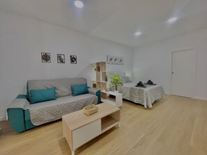 A modern living room with a sofa, a coffee table, a bookshelf, and a bed. - Terrasol Maenoba Playa 4 (Velez-Malaga)