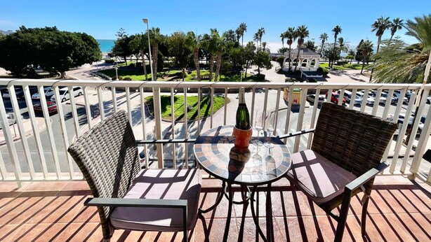 Un balcon agrémenté de meubles en osier, d’une table en verre et d’une bouteille de champagne.