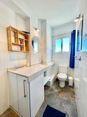 A modern bathroom with a vanity, a mirror, a toilet, and a shower area. - Terrasol EL Nido Frontal AL MAR (Velez-Malaga)
