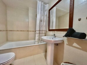 A bathroom with a bathtub, toilet, sink, and a mirror. - Terrasol Tico Baviera Golf LAS Carmelitas (Velez-Malaga)