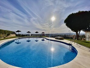 Ein Pool mit klarem Wasser und Blick auf das Meer und ferne Berge.