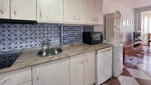 A kitchen with light-colored cabinets, a blue and white patterned backsplash, a stainless steel sink, a black toaster oven, and a white dishwasher. - Terrasol Plazamar 4-9 (Velez-Malaga)