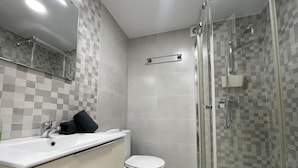 A bathroom with a glass shower enclosure, a white sink, and a toilet. - Terrasol Plazamar 4-9 (Velez-Malaga)