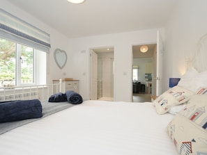 Un dormitorio con cama, espejo con forma de corazón y vistas a una cocina y baño a través de una puerta abierta.