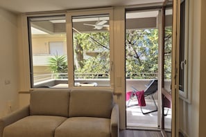 A room with a sofa, a sliding glass door leading to an outdoor balcony with a chair and a table. - Located in one of Viareggio’s most desirable areas, just a few steps from the Pineta di Ponente and approximately a 10-minute walk from the beach, the apartment is an ideal choice for those seeking tranquility and comfort in a well-serviced residential (Viareggio)