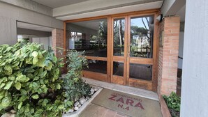 A building entrance with a wooden door, a doormat, and a small garden area. - Located in one of Viareggio’s most desirable areas, just a few steps from the Pineta di Ponente and approximately a 10-minute walk from the beach, the apartment is an ideal choice for those seeking tranquility and comfort in a well-serviced residential (Viareggio)