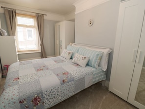A bedroom with a bed, curtains, a wardrobe, and a window.