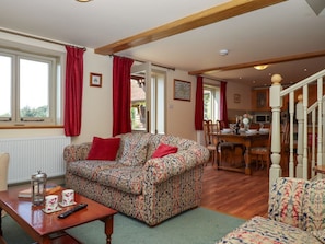 A living room with a patterned sofa, a wooden coffee table, and a dining area with a wooden table and chairs.