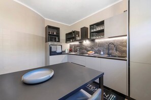 Una cocina moderna con encimera de mármol, horno empotrado y pileta con grifo.