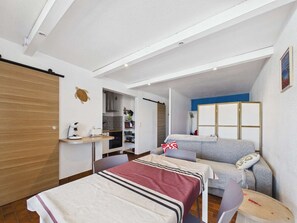 A compact room with a bed, a small table, a chair, a kitchenette, and a wardrobe. - Charming 2-Bedroom Cabin Apartment with Private Parking (Marseillan-Plage)