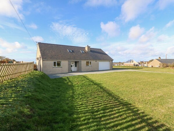 Une maison de plain-pied avec un garage, un toit en pente et une pelouse bien entretenue.